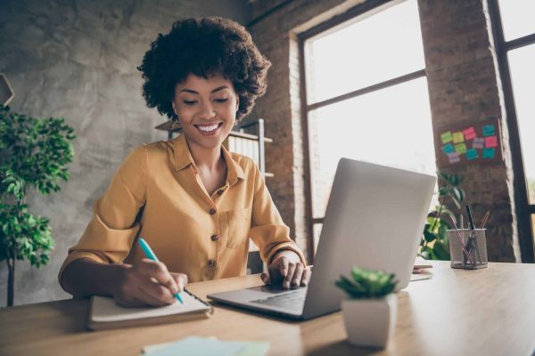 A black woman showcasing Resume Gems at her desk with a laptop.