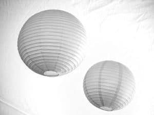 Two white paper lanterns hanging against a white background.