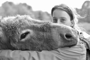 A woman hugging a donkey in black and white in Vermont.
